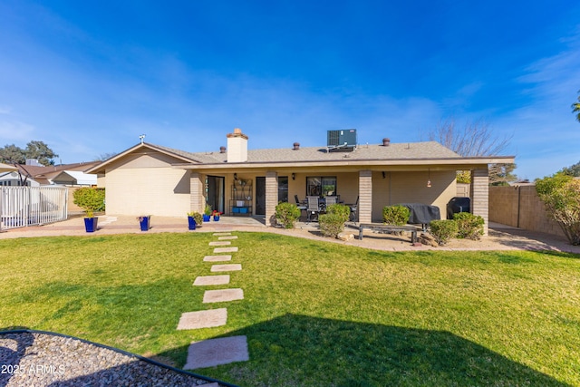 rear view of property featuring a yard, central AC, and a patio area