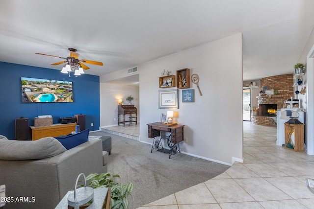 tiled living room featuring a fireplace and ceiling fan