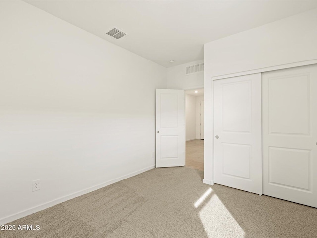 unfurnished bedroom featuring light colored carpet and a closet