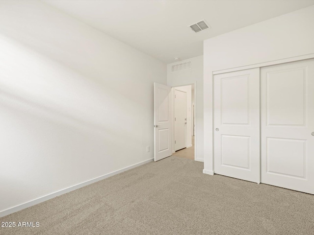 unfurnished bedroom with light carpet and a closet