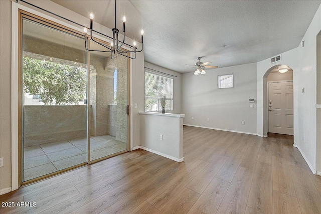 29606 N Tatum Blvd N Unit 265, Cave Creek, AZ 85331 - empty room with wood finished floors, arched walkways, ceiling fan, a chandelier, and a textured ceiling