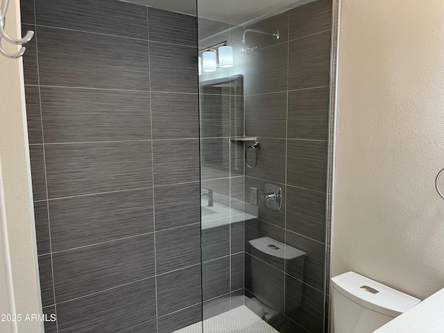 bathroom featuring toilet and tiled shower