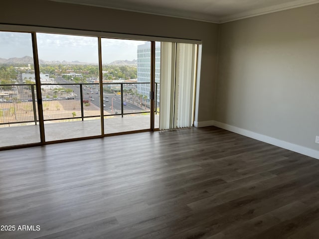 unfurnished room with ornamental molding, dark wood-style flooring, a mountain view, and baseboards
