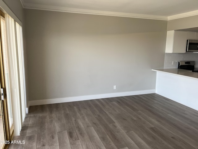 unfurnished dining area featuring crown molding, dark wood-style floors, baseboards, and healthy amount of natural light