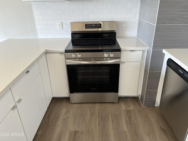 kitchen featuring stainless steel appliances, wood finished floors, white cabinetry, and decorative backsplash