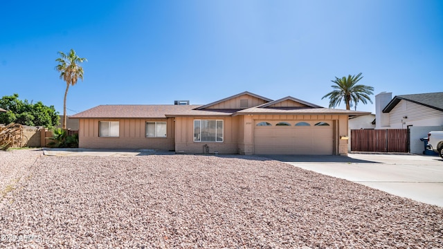 ranch-style house featuring fence, brick siding, board and batten siding, an attached garage, and driveway