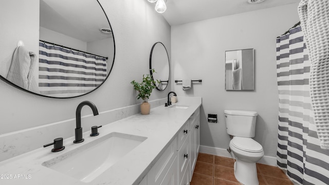 full bathroom with double vanity, a sink, tile patterned floors, and toilet