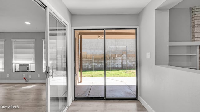 doorway with baseboards, wood finished floors, and cooling unit