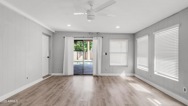 empty room with light wood-style floors, a ceiling fan, and baseboards