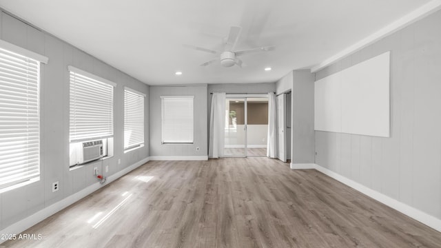 interior space with a ceiling fan, baseboards, light wood-style flooring, and cooling unit