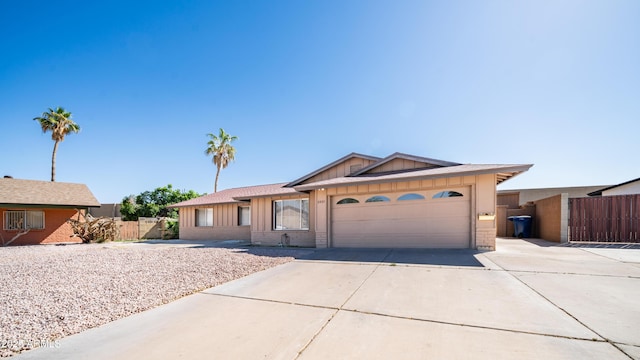 ranch-style home featuring board and batten siding, driveway, brick siding, fence, and an attached garage
