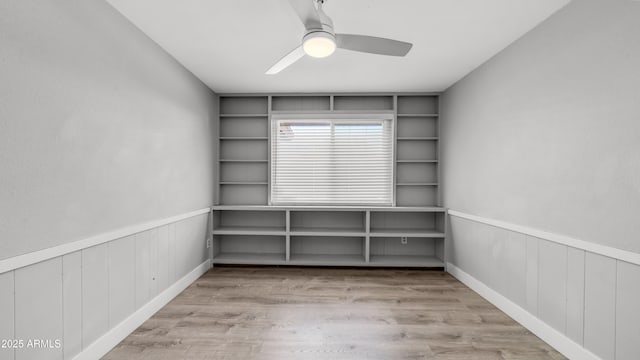 unfurnished room featuring a ceiling fan, wainscoting, and wood finished floors