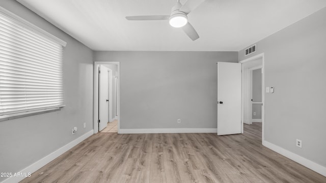 unfurnished bedroom with baseboards, multiple windows, wood finished floors, and visible vents