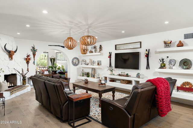 living room featuring light hardwood / wood-style flooring and a stone fireplace