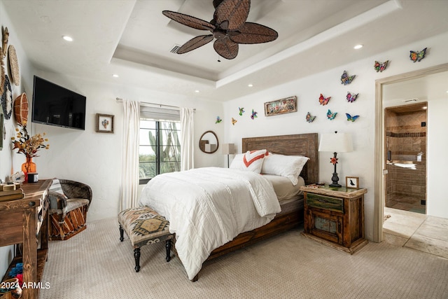 bedroom featuring light carpet, ceiling fan, connected bathroom, and a tray ceiling