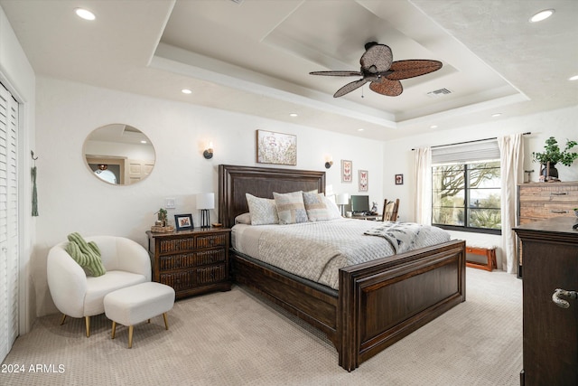 bedroom featuring ceiling fan, light colored carpet, and a raised ceiling