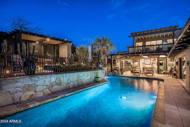 pool at night featuring a patio area