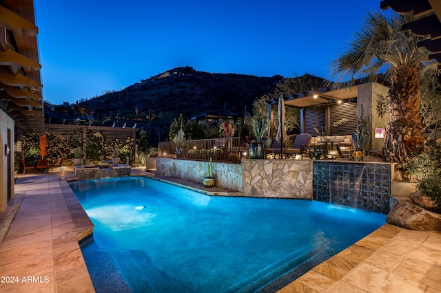 pool at dusk with a patio area and a mountain view