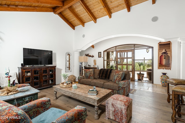 living room featuring beam ceiling, hardwood / wood-style flooring, high vaulted ceiling, ornate columns, and wooden ceiling