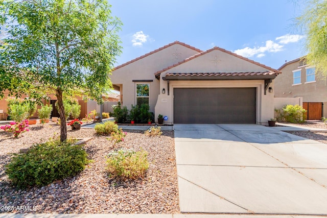 mediterranean / spanish house with fence, an attached garage, stucco siding, concrete driveway, and a tiled roof