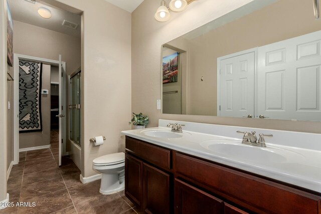 bathroom featuring double vanity, visible vents, toilet, and a sink