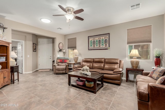 living room with light tile patterned floors, visible vents, baseboards, and ceiling fan