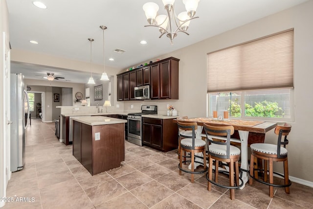 kitchen featuring visible vents, a peninsula, stainless steel appliances, light countertops, and dark brown cabinets