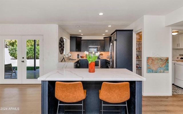 kitchen featuring french doors, sink, stainless steel appliances, light stone counters, and washer / clothes dryer