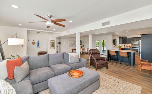 living room featuring french doors, light wood-type flooring, and ceiling fan