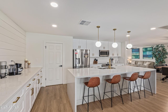2033 E Janice Way, Phoenix, AZ 85022 - kitchen with appliances with stainless steel finishes, a kitchen bar, white cabinets, light wood-type flooring, and open floor plan