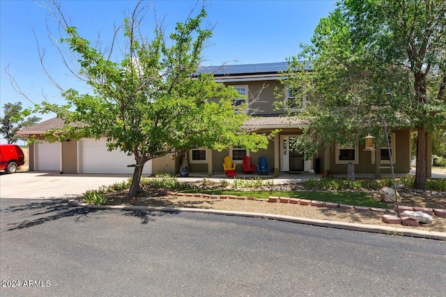 view of property hidden behind natural elements with a garage, a porch, and solar panels