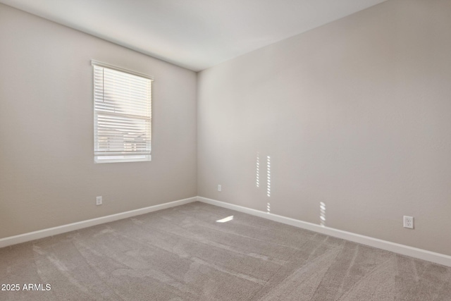 carpeted empty room featuring baseboards