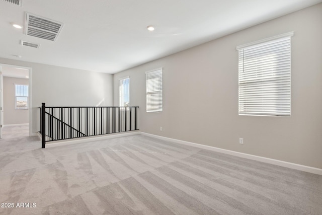 empty room with light carpet, visible vents, and baseboards