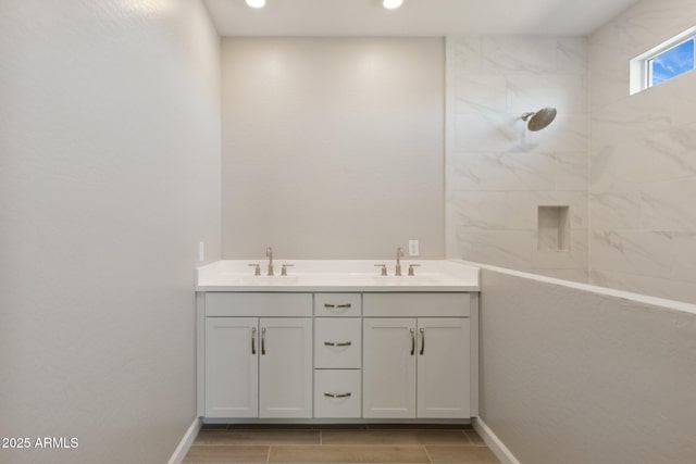 bathroom featuring a sink, tiled shower, recessed lighting, and double vanity