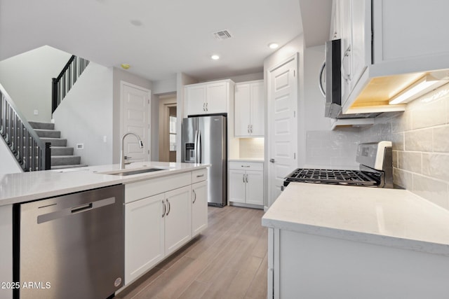 kitchen with tasteful backsplash, visible vents, appliances with stainless steel finishes, light wood-style floors, and a sink