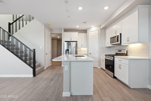 kitchen featuring visible vents, wood finish floors, a sink, stainless steel appliances, and tasteful backsplash