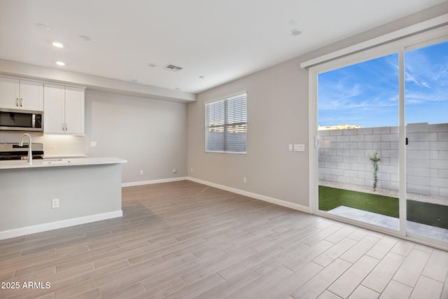 kitchen with visible vents, light wood-style floors, appliances with stainless steel finishes, light countertops, and baseboards