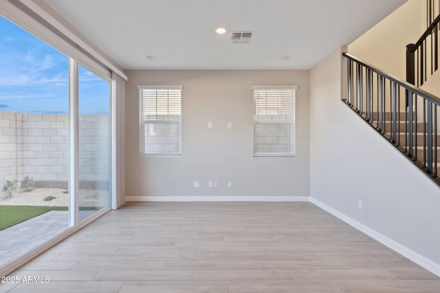 spare room featuring visible vents, stairway, baseboards, and light wood-style floors