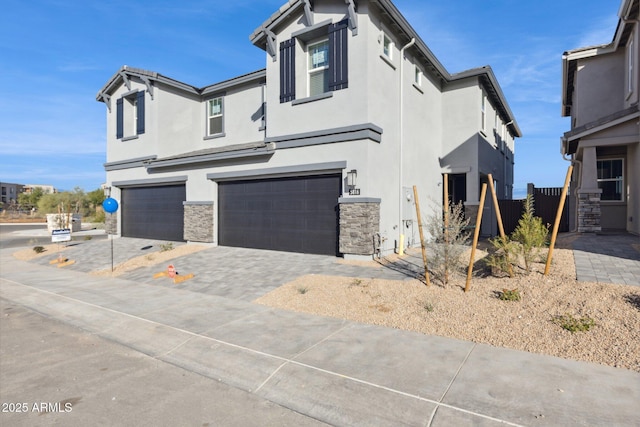 view of front of home featuring stucco siding, stone siding, a garage, and decorative driveway