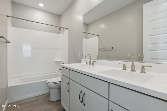 bathroom with toilet, shower / bathing tub combination, wood tiled floor, and a sink