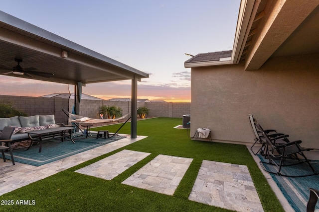 yard at dusk featuring outdoor lounge area, central air condition unit, ceiling fan, and a patio area