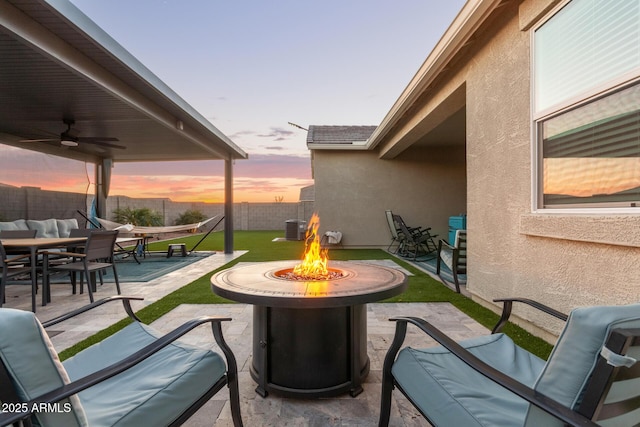 patio terrace at dusk featuring central AC, ceiling fan, and an outdoor fire pit