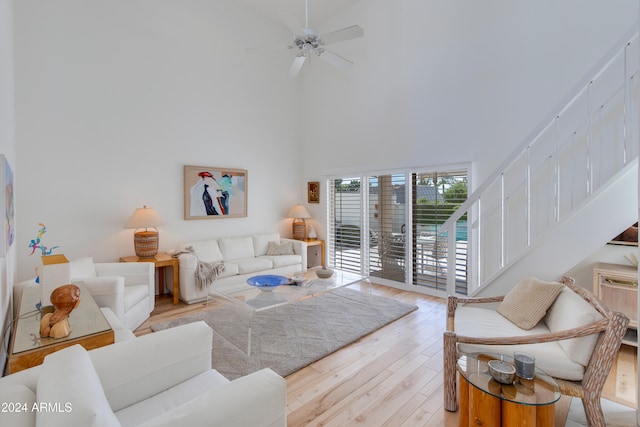 living room featuring a towering ceiling, light wood-type flooring, and ceiling fan