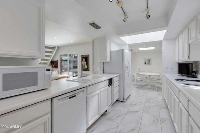 kitchen with sink, rail lighting, white cabinetry, white appliances, and a skylight