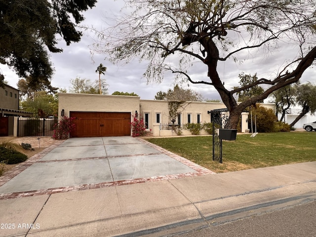 view of front of home with fence, concrete driveway, a front yard, stucco siding, and a garage