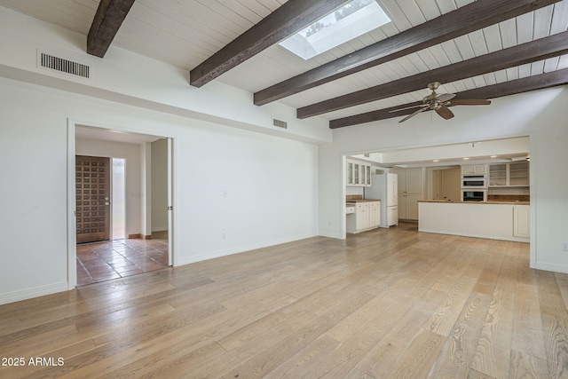 unfurnished living room featuring visible vents, light wood-style flooring, a skylight, and baseboards