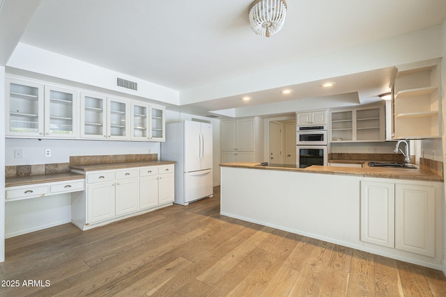 kitchen with visible vents, stainless steel double oven, open shelves, freestanding refrigerator, and a sink