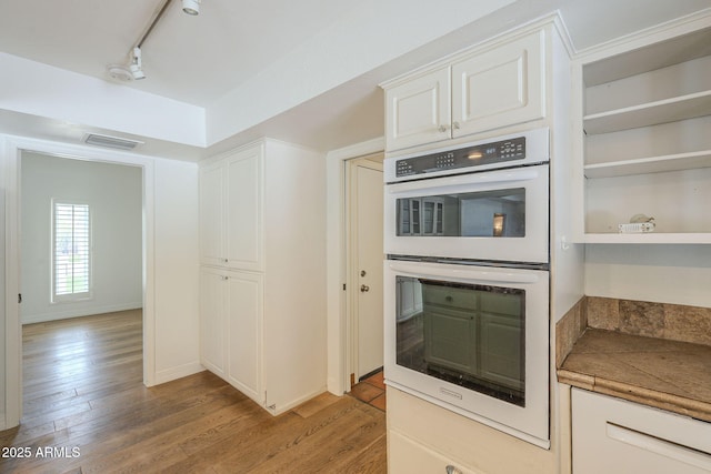 kitchen featuring visible vents, track lighting, double oven, light wood-style flooring, and white cabinets