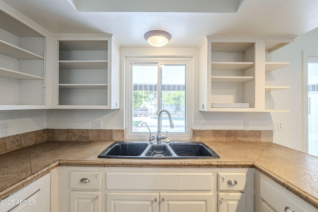 kitchen with a sink, white cabinetry, and open shelves