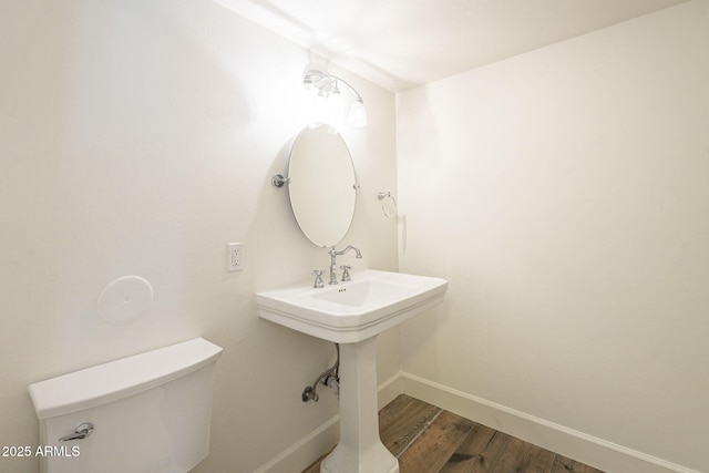 bathroom with toilet, wood finished floors, and baseboards